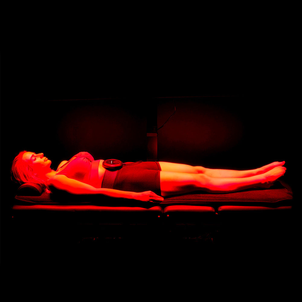 Lady laying under red light with CELLER8 around waist