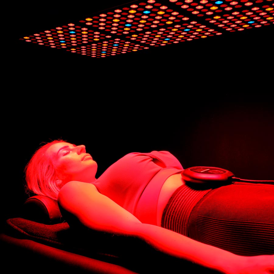 Lady laying under red light panel with CELLER8 around waist