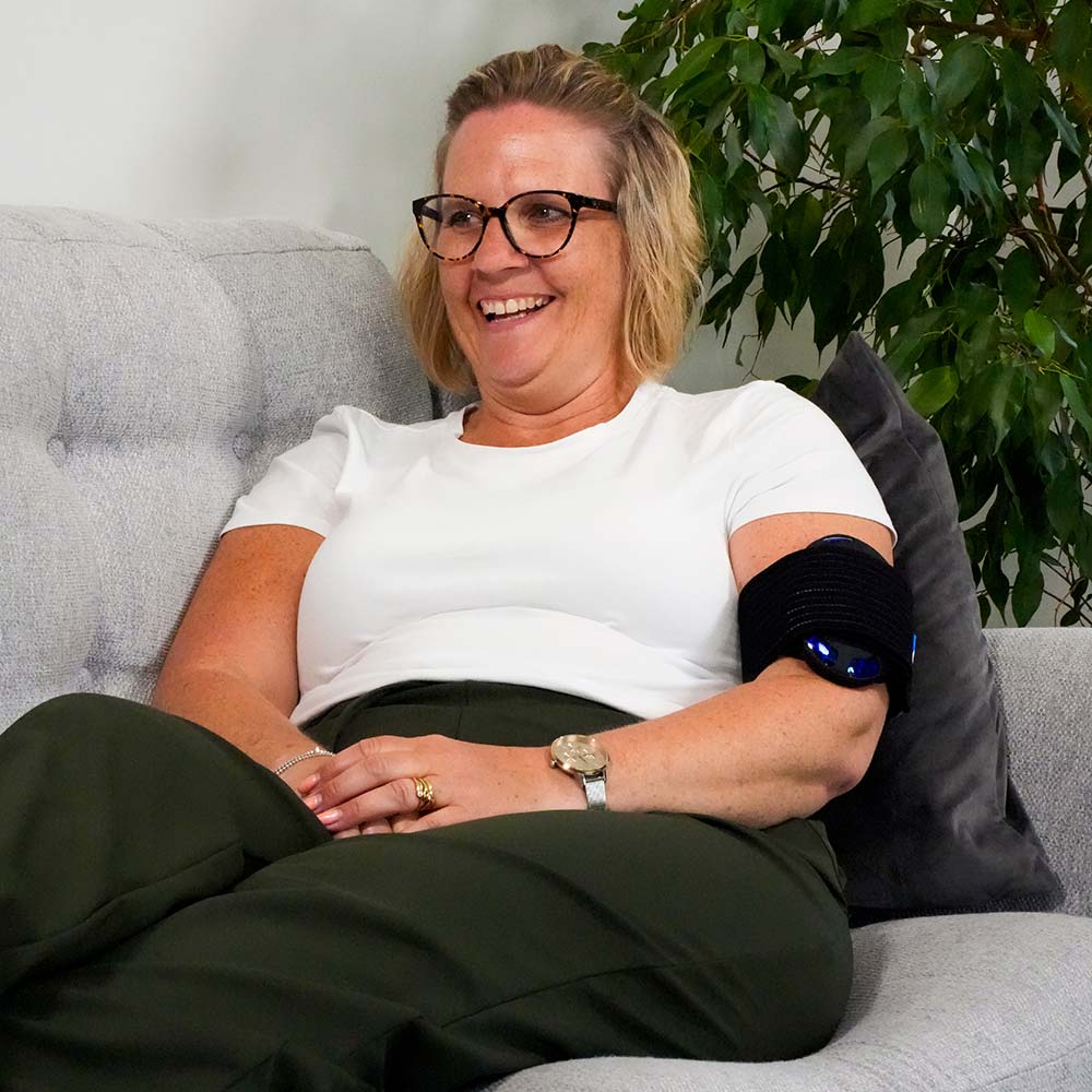 Lady sat on sofa with OSKA Pulse 90 minute on left arm